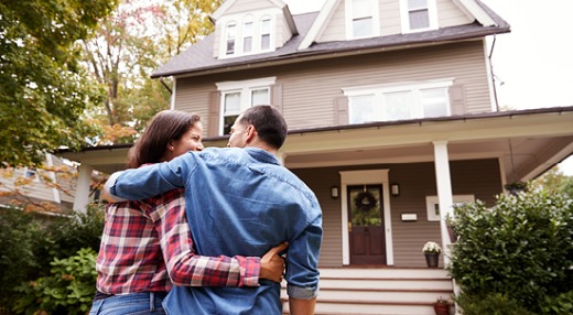 Couple standing outside their new home.