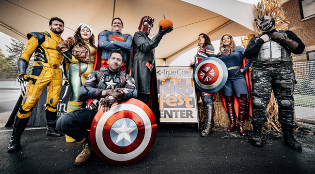 Various marvel superheroes and Superman surrounding a sign that says Kids Fest.
