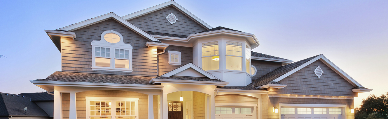 Outdoor view of a large, tan house during the evening. 